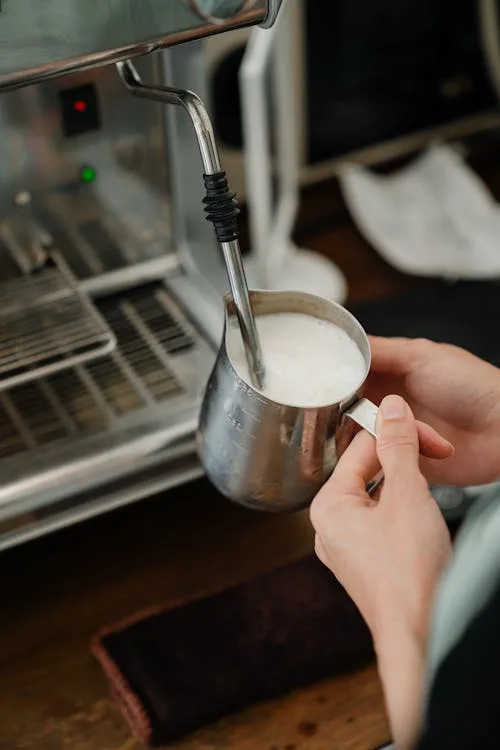 Steaming milk with a pitcher and steam wand at a home espresso setup
