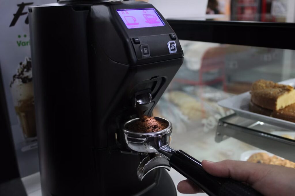 Barista adjusting espresso grinder setting while watching shot time on a timer